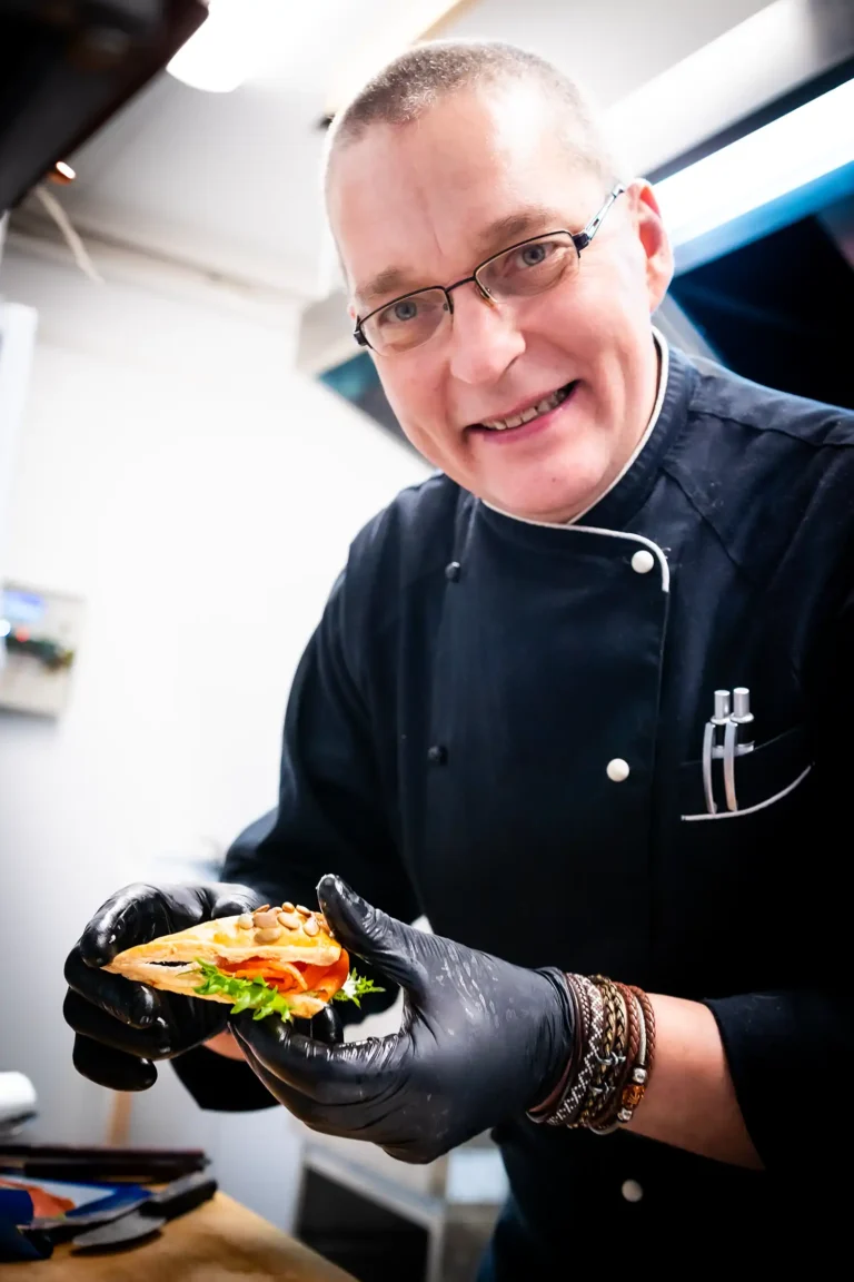 Fargerike eventyr catering sin rockekokk Alik viser frem en snitte med nydelig laks med et stort smil.